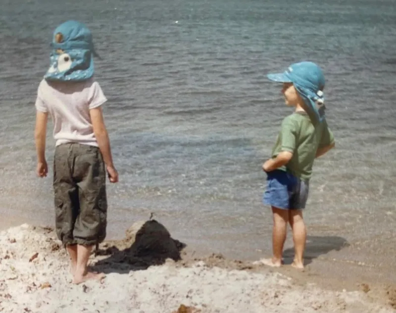 Emilee and Toby as kids in sun hats at the water's edge